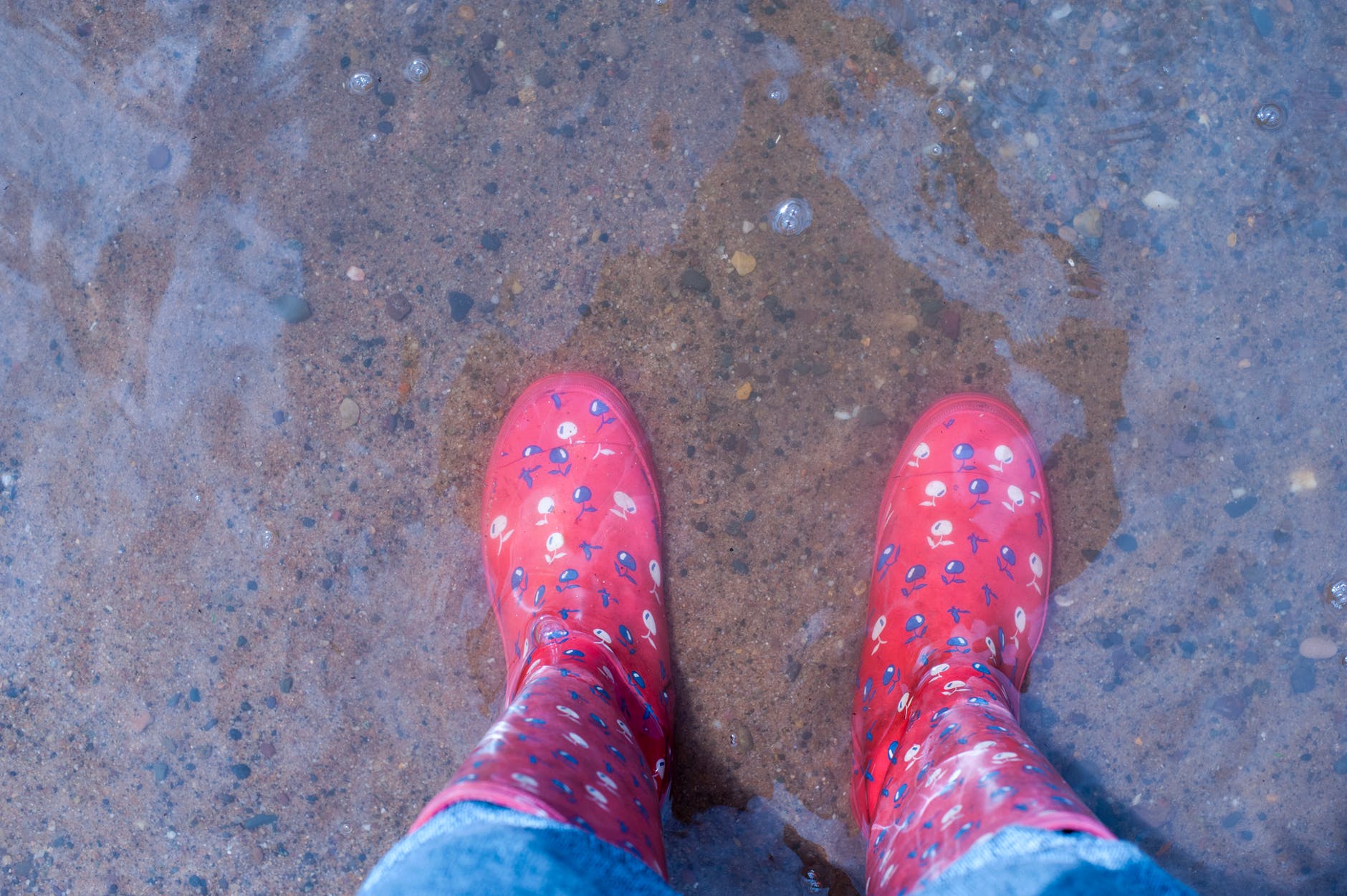 person wearing pink knee high rain boots standing on brown floor